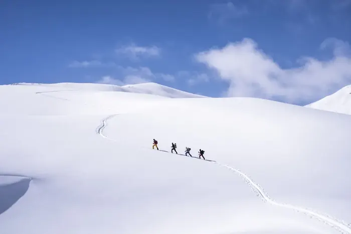 Trekkers crossing a snowy mountain ridge