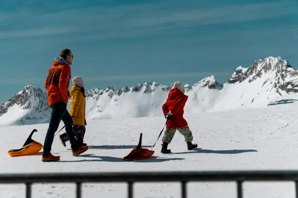 A family walking with sleds across the snow
