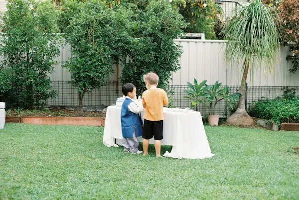 Two kids standing together at a backyard table