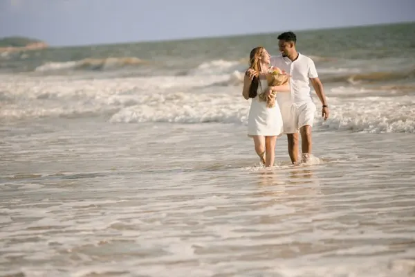 A couple walking through the shallows at the shoreline