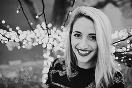 A woman smiling beside the lit tree